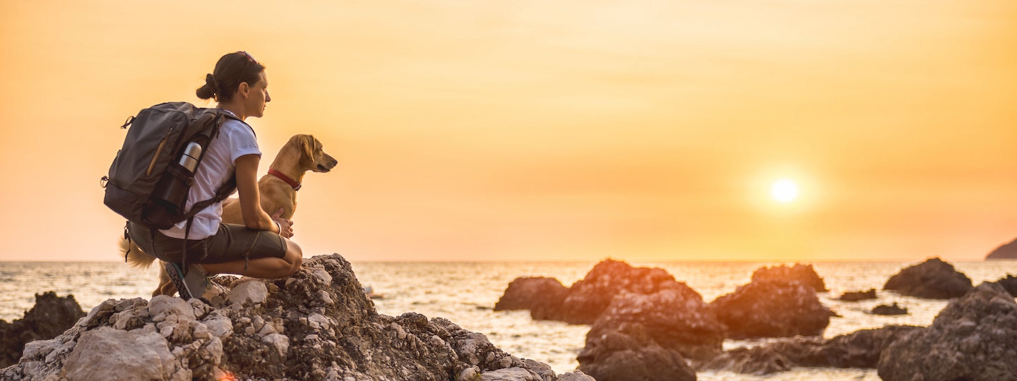 Woman and dog hiking on the beach cliffs